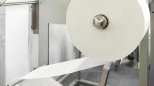 paper being processed in factory with industrial metal hose components