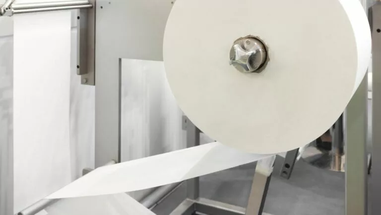 paper being processed in factory with industrial metal hose components